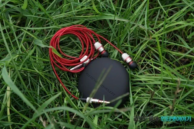 잔디 위에 놓여진 이어폰과 파우치 